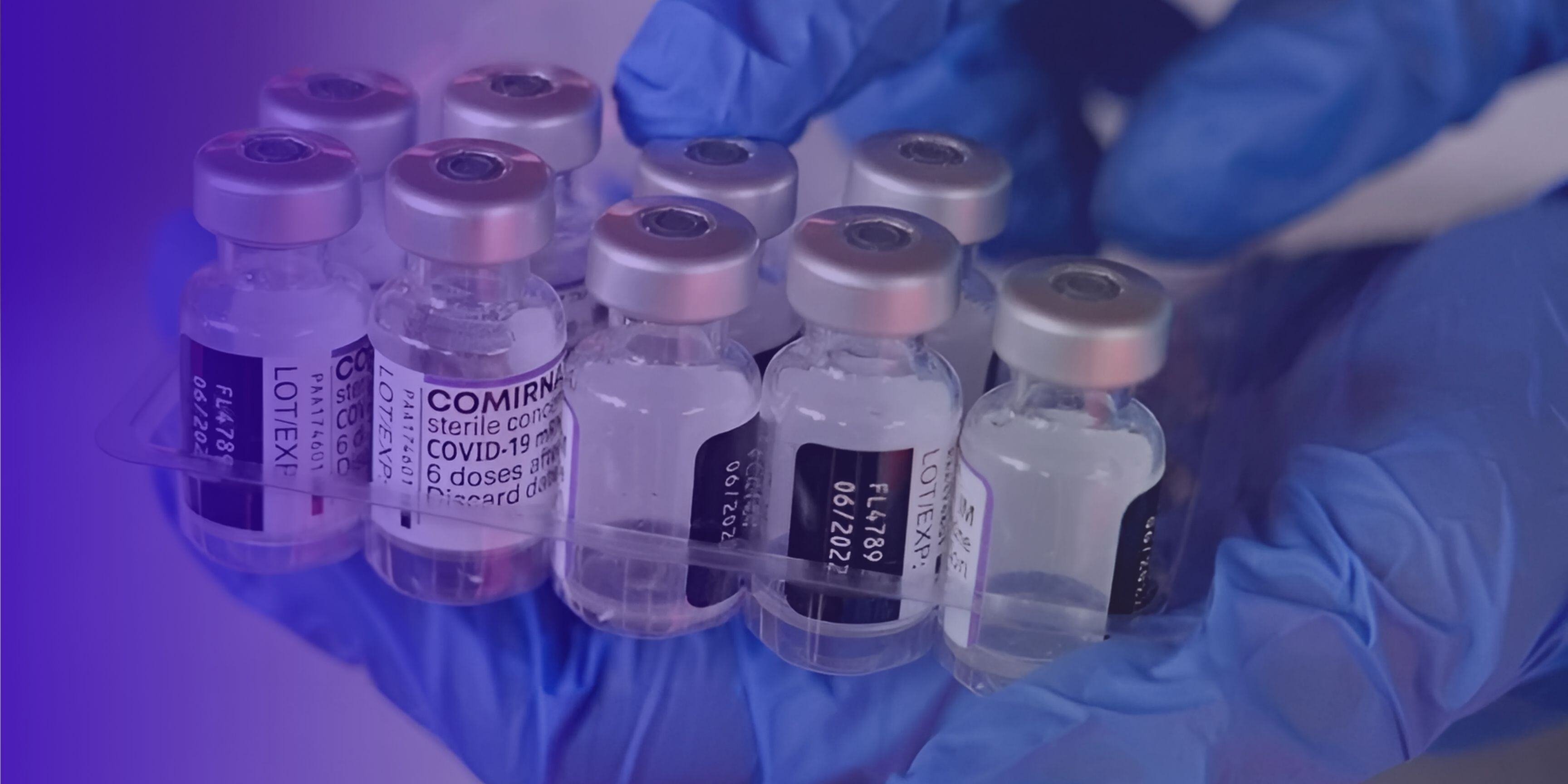 COVID-19 vaccine vials held by a gloved hand, illustrating strict cold chain monitoring.