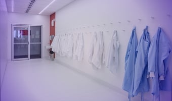 Lab coats hanging in a sterile gowning area, symbolizing access control in clean environments.