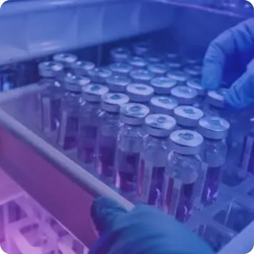 Storing vaccine vials in a freezer by a technician wearing protective gloves.