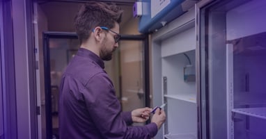 Technician installing a temperature probe in a laboratory refrigerator for ATEK monitoring system.