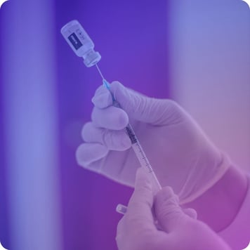 Preparing a syringe with a vaccine by a healthcare professional wearing sterile gloves.